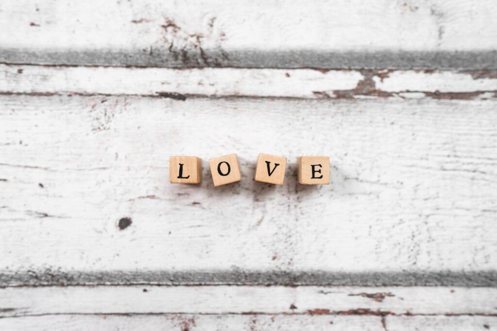 LOVE spelled using wooden cubes on white distressed background