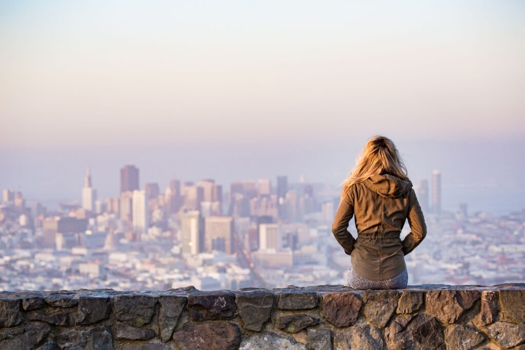 Young woman sitting on a wall overlooking a city