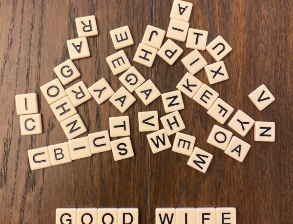 scattered scrabble tiles on brown wooden surface spelling good wife