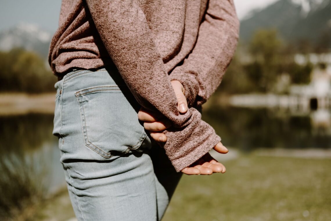 Person in brown sweater and blue denim jeans
