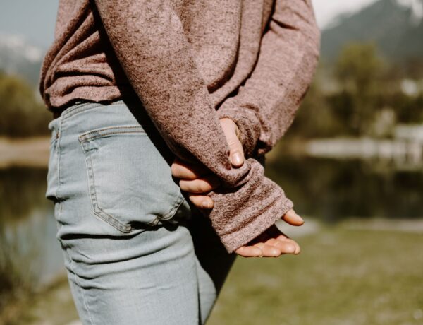Person in brown sweater and blue denim jeans