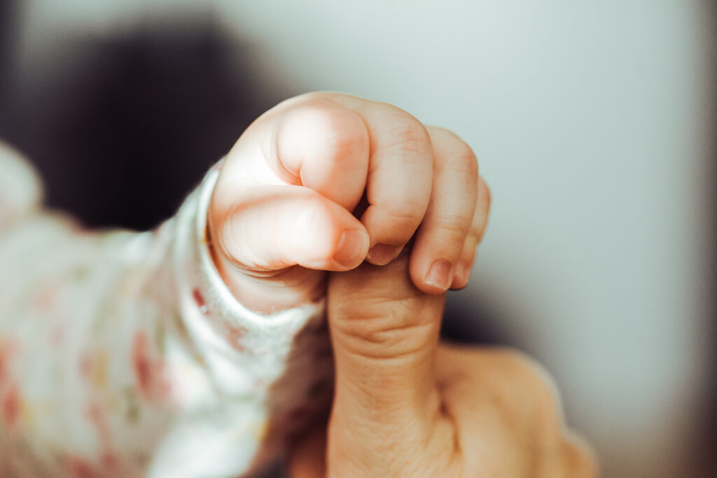 Baby holding adult finger