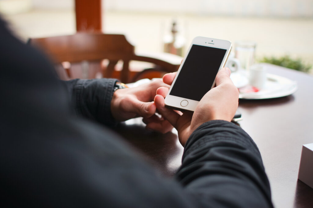 Person sitting at a table holding a mobile phone