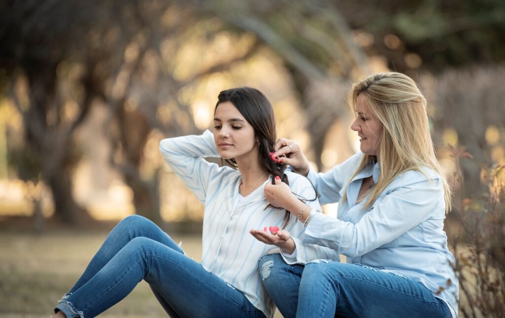  how to help a teen diagnosed with an anxiety disorder? woman brushing hair of girl while sitting on green field 