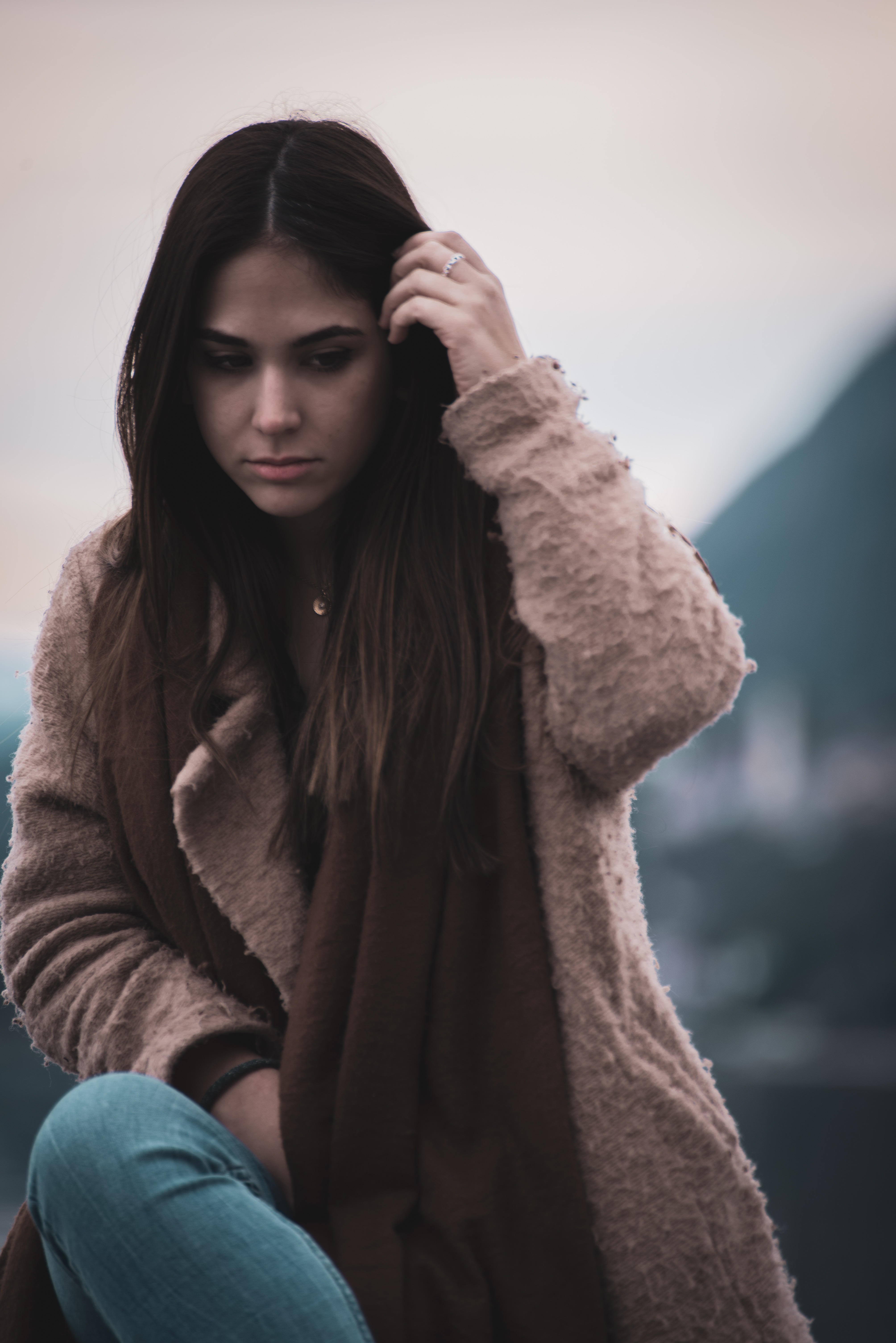 Teen diagnosed with an anxiety disorder in a brown fur coat sitting and holding her hair
