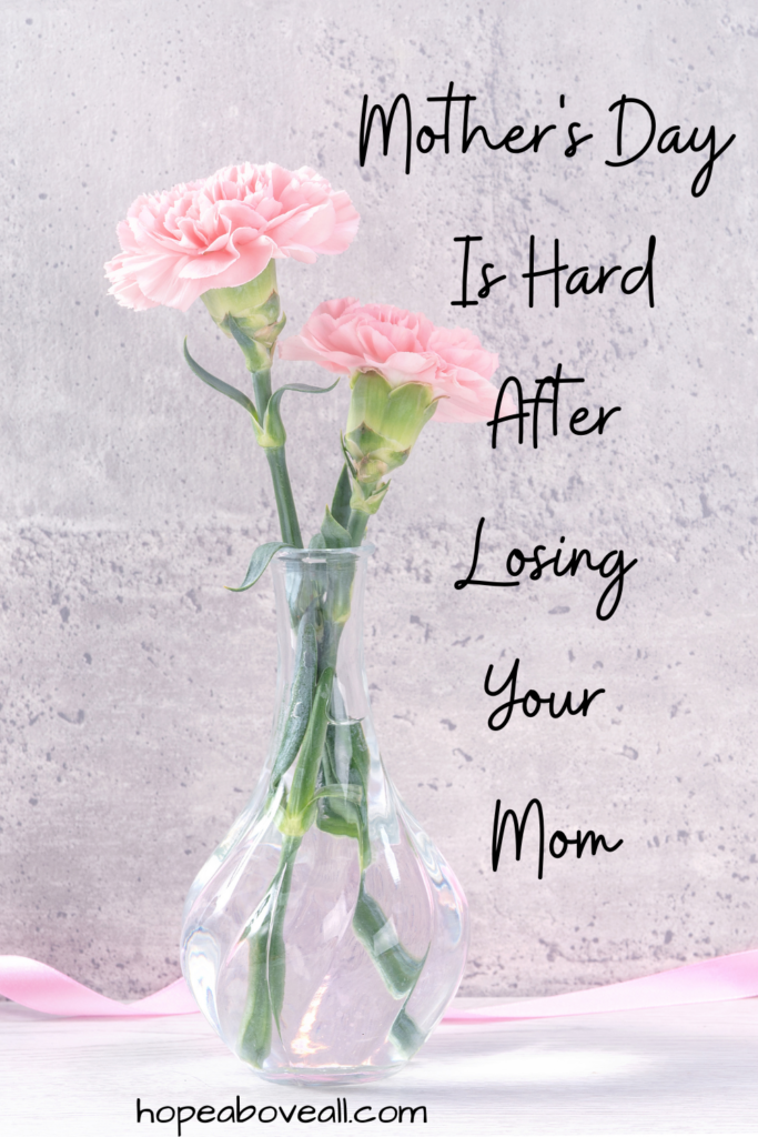 Pin image of 2 pink carnation flowers in a glass vase.  The title of the blog post:
Mother's Day Is Hard After Losing Your Mom, is on the right side of the image.