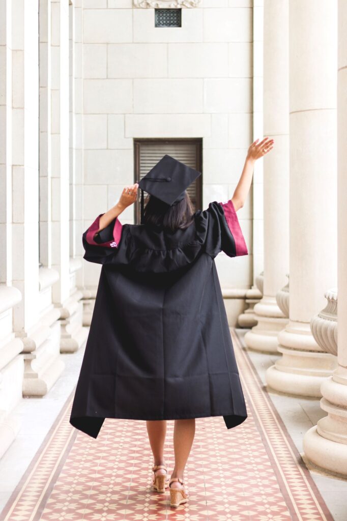 Photo of the back of a female graduate dressed in a black graduation gown.