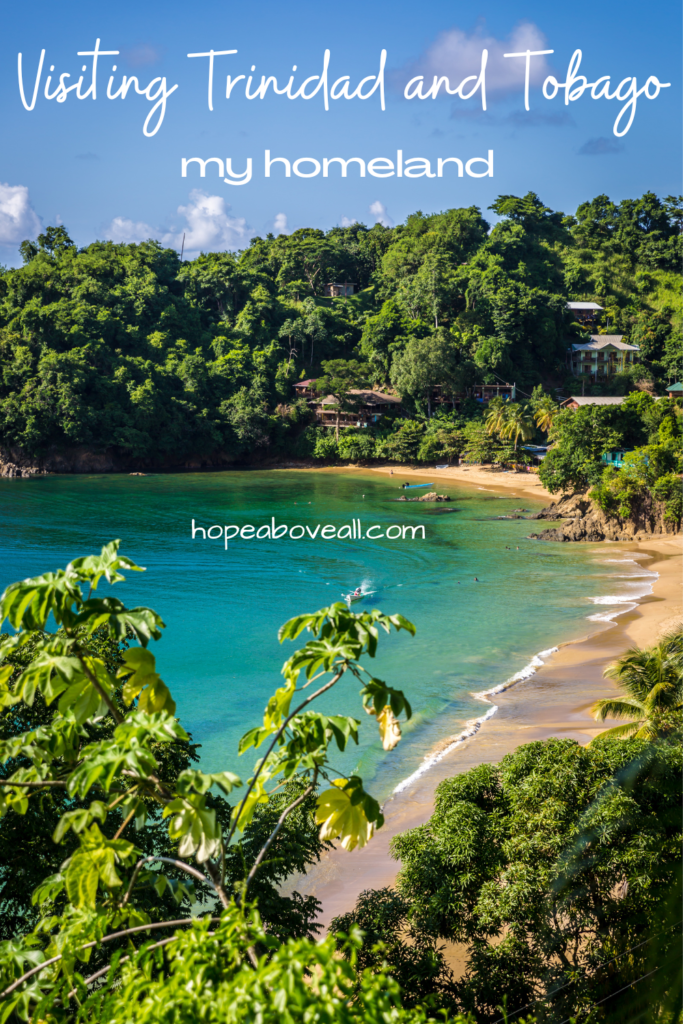 Beautiful beach in Trinidad, surrounded by lush green foliage.  Pin title: Visiting Trinidad and Tobago, My Homeland, is at the top of the image. 