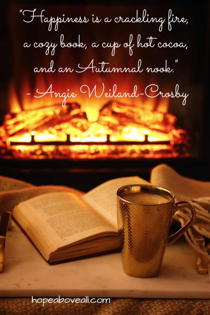 Book and cup of hot cocoa next to a fireplace.