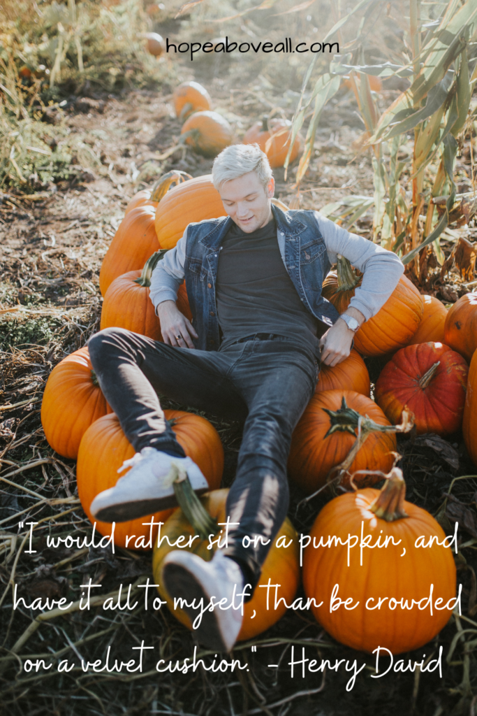 Young man sitting on a chair made out of pumpkins.