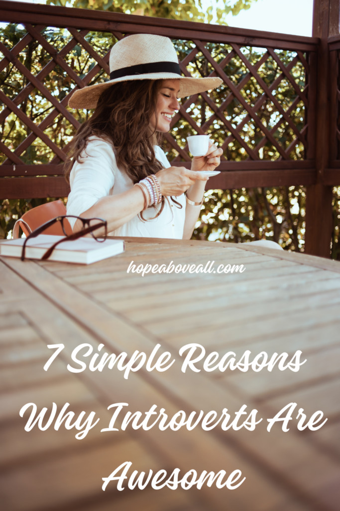 Introvert woman sitting at a table drinking coffee with title of blog at the bottom: 7 Simple Reasons Why Introverts Are Awesome