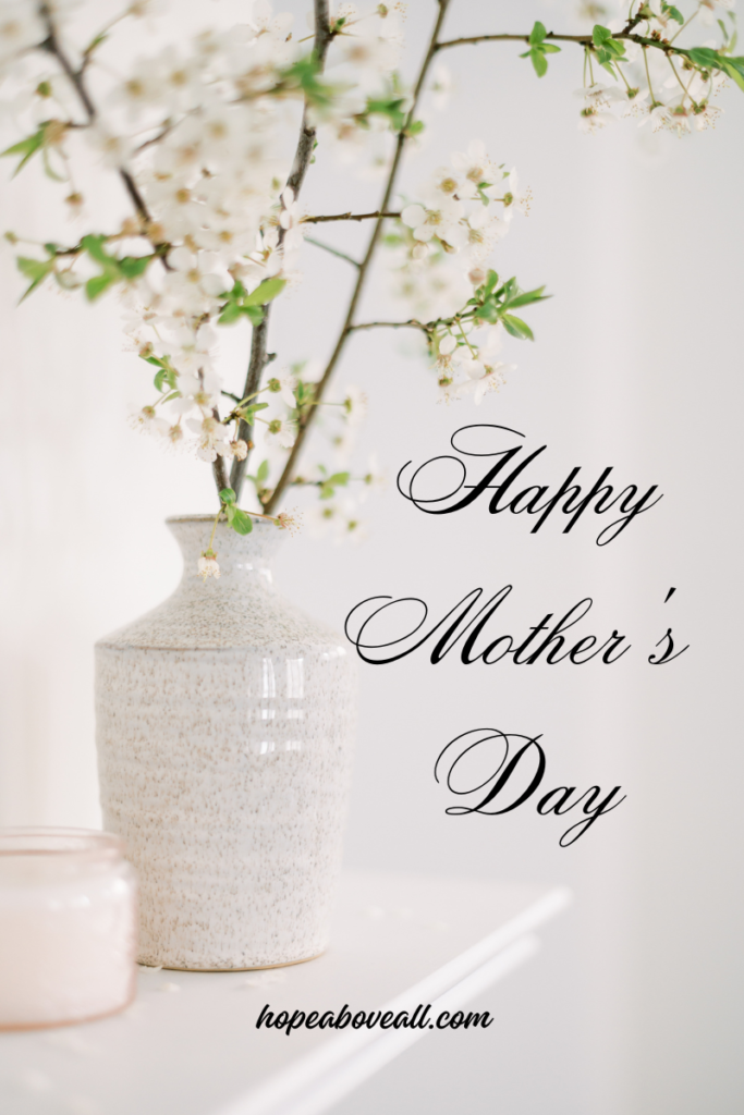 Elegant white with brown speckles vase with cherry blossom plant in it.  Happy Mother's Day is written on the right side.