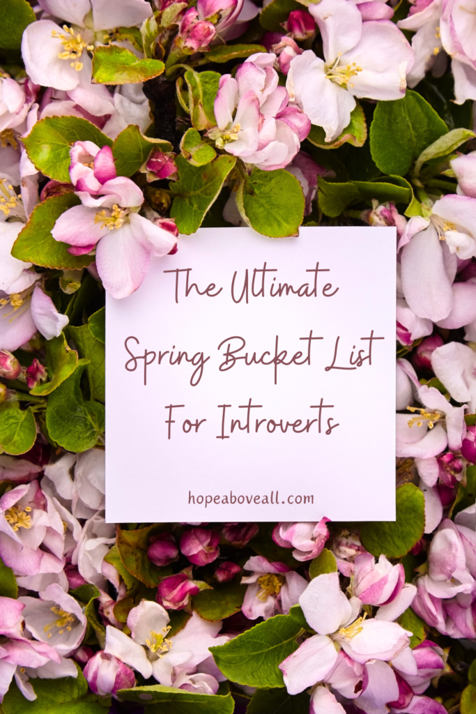 image of beautiful spring flowers with title of blog post "The Ultimate Spring Bucket List For Introverts" in the middle