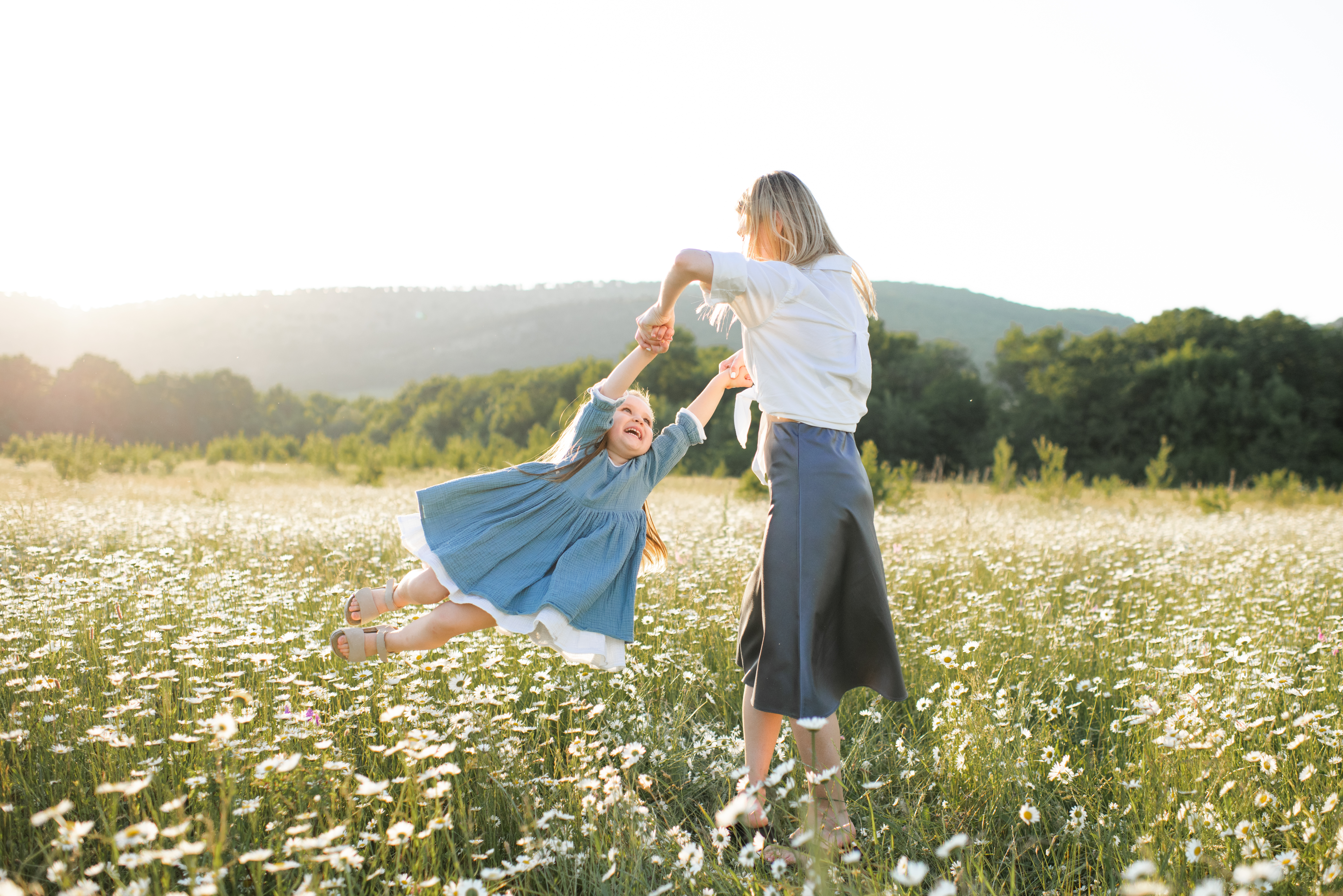 Young mother having fun with kid girl daughter in blooming meadow