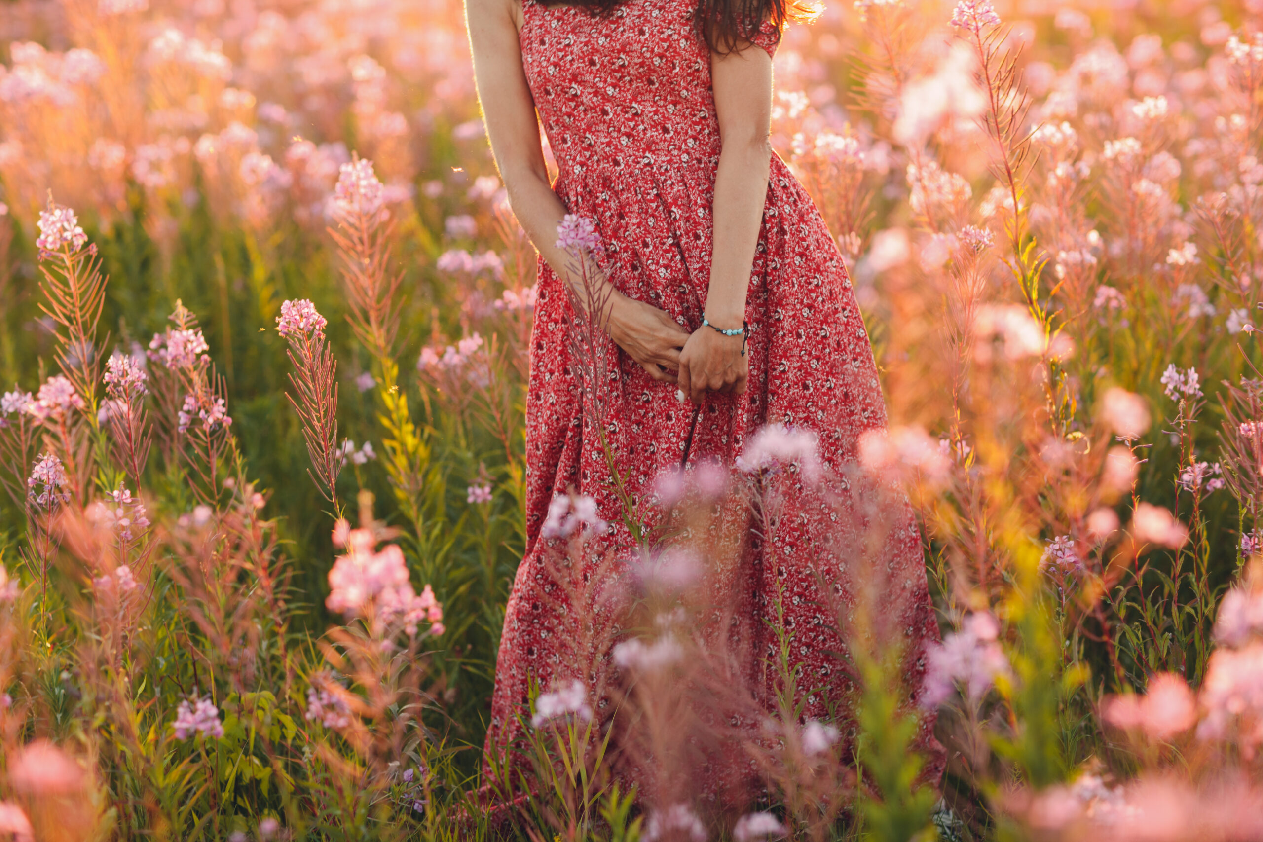 Woman in red and white floral sleeveless dress standing on flower field