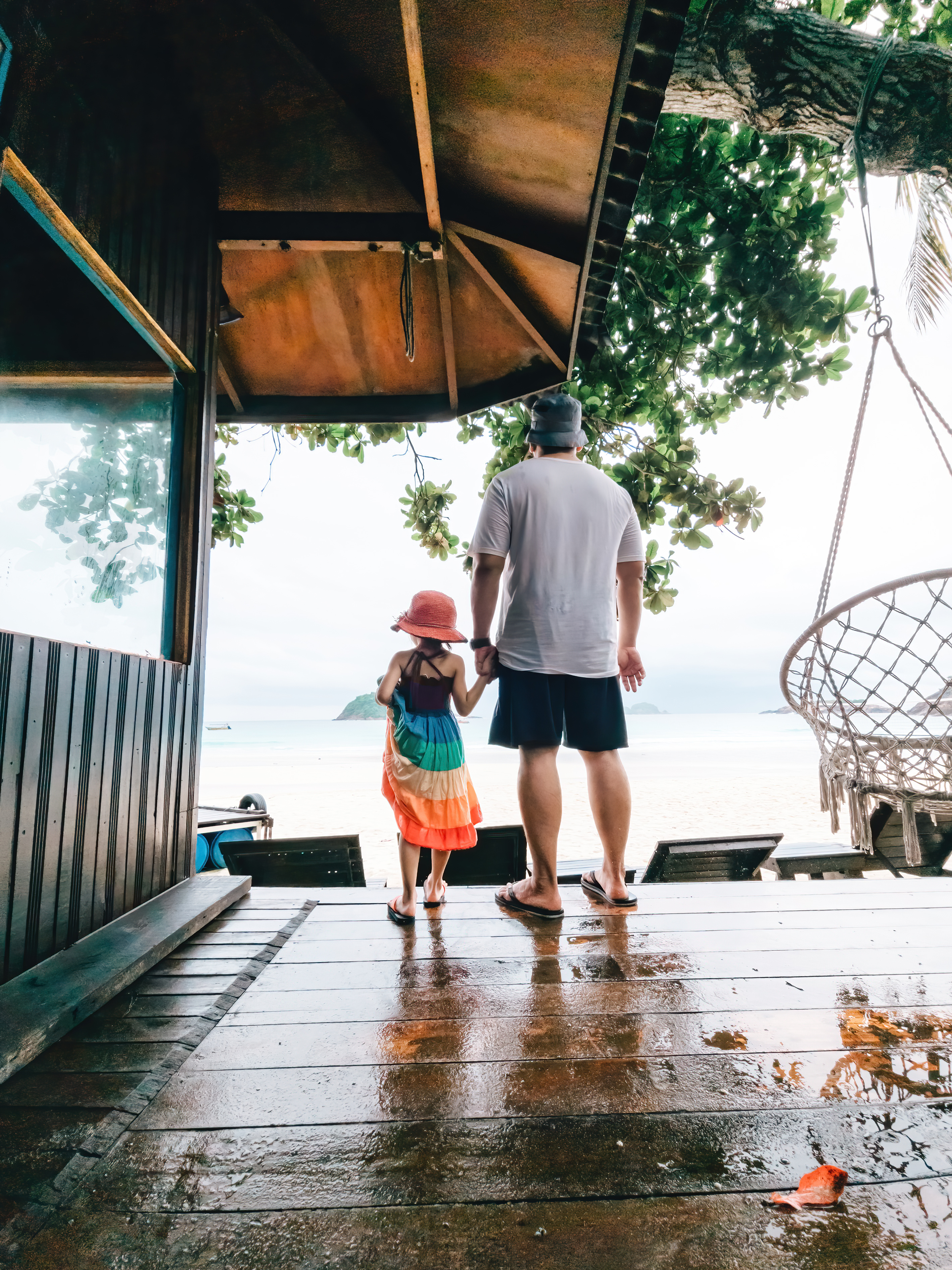 Man and little girl standing on wooden dock at the beach