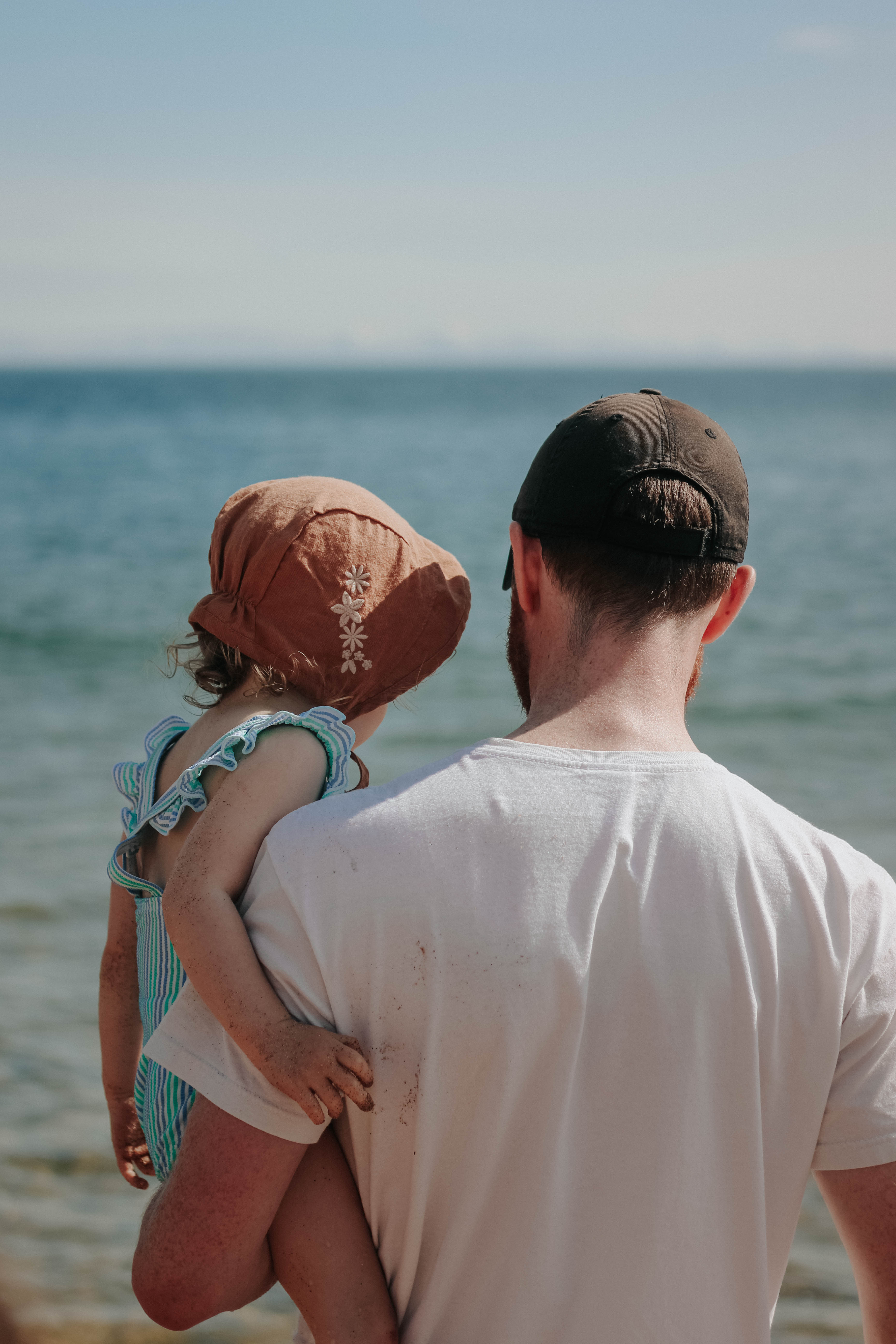 Man in white shirt holding child in blue swimsuit